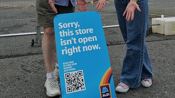 Cllrs Grahame Andrew and Jayne Davies at the sign showing the old ALDI store has closed