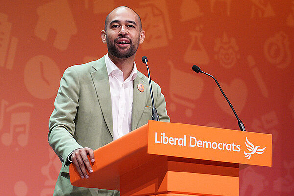 Josh Babarinde MP stands at a lecturn at Conference delivering a speech
